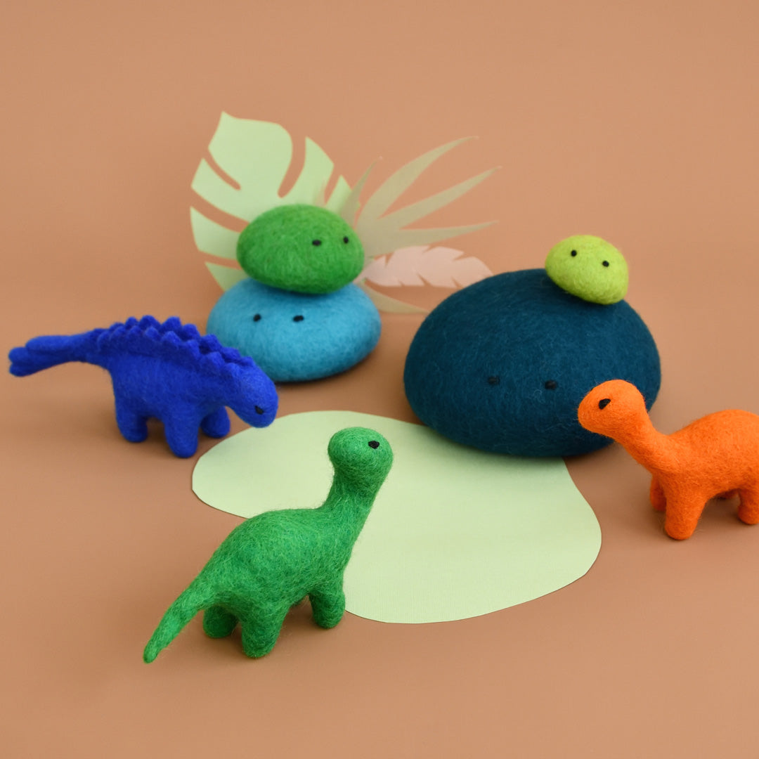 Collection of mini felt dinosaur toys around a waterhole