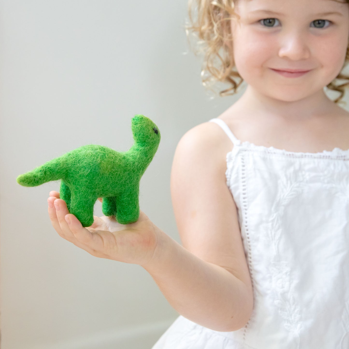 Girl holding mini green felt dinosaur